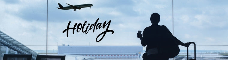 Traveller at an airport window watching a plane take off with the word ‘Holiday’.