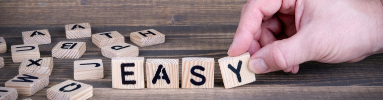 Hand arranging wooden letter tiles spelling the word ‘Easy’.